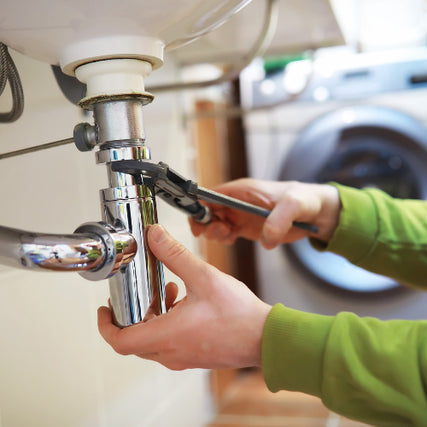 Plumbing SuppliesA wrench being used on a pipe underneath a sink.